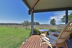 Un espace extérieur abrité, aménagé pour s’asseoir, avec vue sur un vignoble.