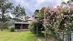 A house with a covered porch, a lawn, and flowering bushes.