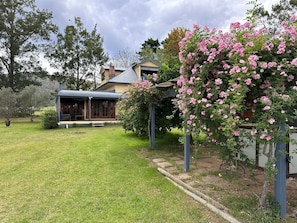 A house with a covered porch, a lawn, and flowering bushes.