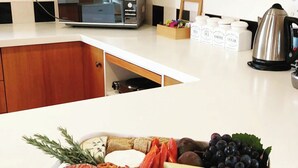 Uma bancada de cozinha com uma tábua de frios, um micro-ondas e uma chaleira.