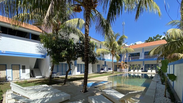 A resort with a swimming pool, lounge chairs, and palm trees. - Kura Kura Divers Lodge (Karangasem)
