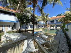 Un resort con piscina, sillas de descanso y palmeras.