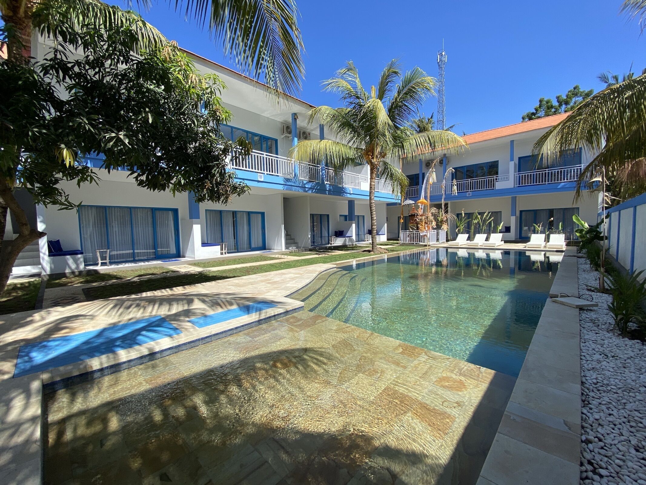 Ein Hotel mit Swimmingpool, Palmen und blauem Himmel.