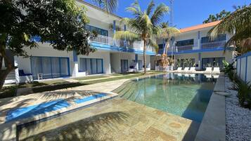 Ein Hotel mit Swimmingpool, Palmen und blauem Himmel.