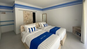 A hotel room with two beds, a wooden headboard, a large mirror, and a wardrobe with a sliding door. - Kura Kura Divers Lodge (Karangasem)