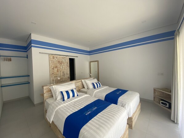 A hotel room with two beds, a wooden headboard, a large mirror, and a wardrobe with a sliding door.