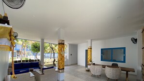 A spacious room with a reception area, a pool view, and a blue-framed window. - Kura Kura Divers Lodge (Karangasem)