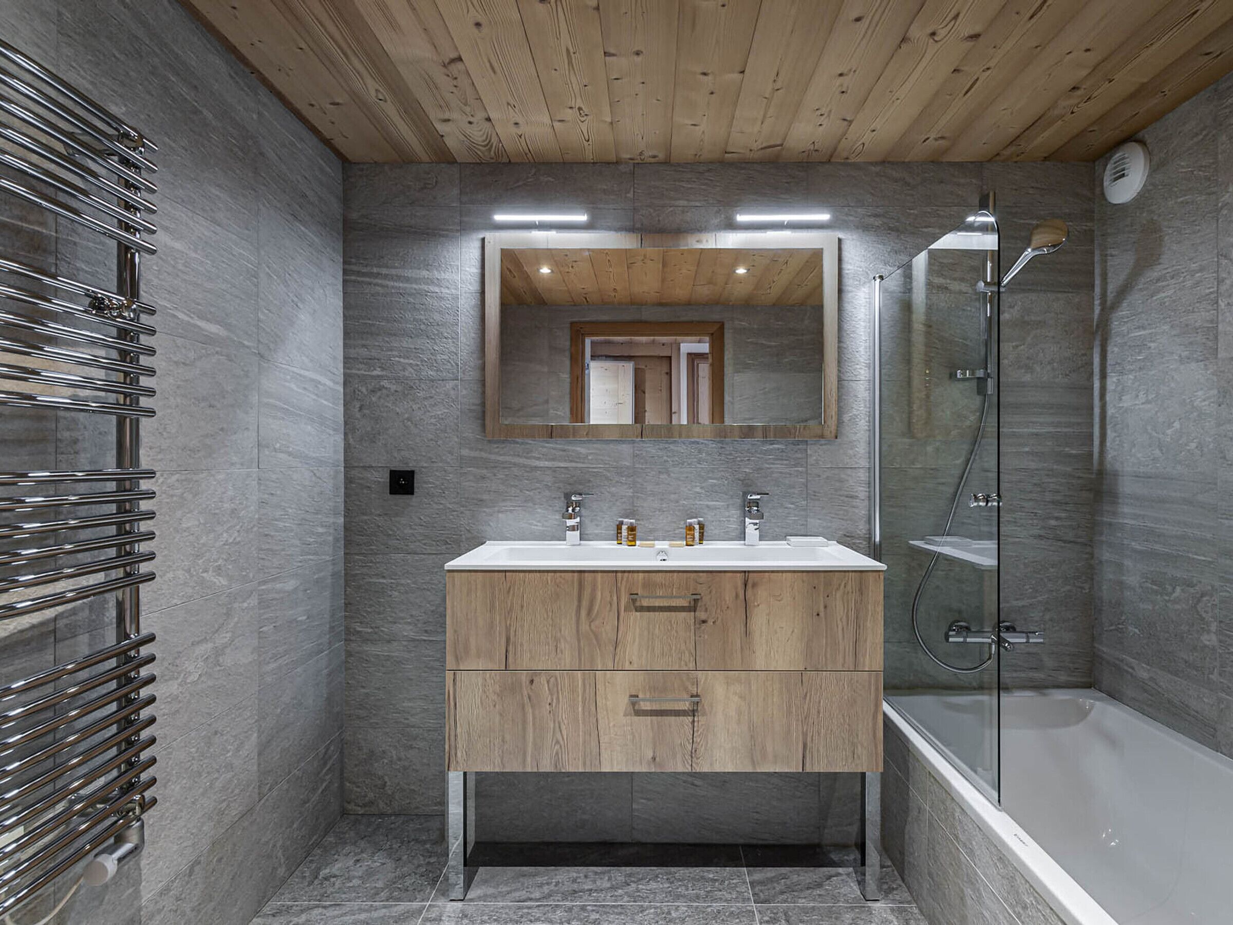 Une salle de bain moderne avec un meuble-lavabo en bois, une cabine de douche en verre et un lavabo intégré.