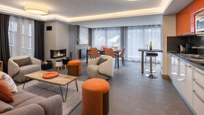 Een moderne woonkamer met een open haard, banken, een salontafel en een eethoek met stoelen en een tafel.