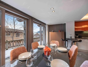 A dining area with a table set for four, large windows, and a view of buildings and mountains.