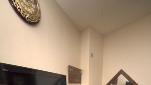 A hotel room with a flat-screen TV mounted on the wall, a wooden dresser, a vanity with a mirror, and a chair. - Downtown Hotel (Dubai)