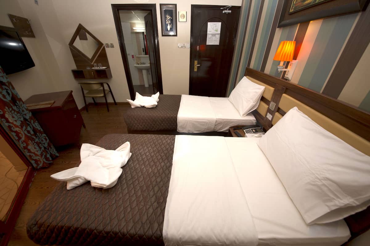 A hotel room with two beds, a TV, a desk, and a chair.