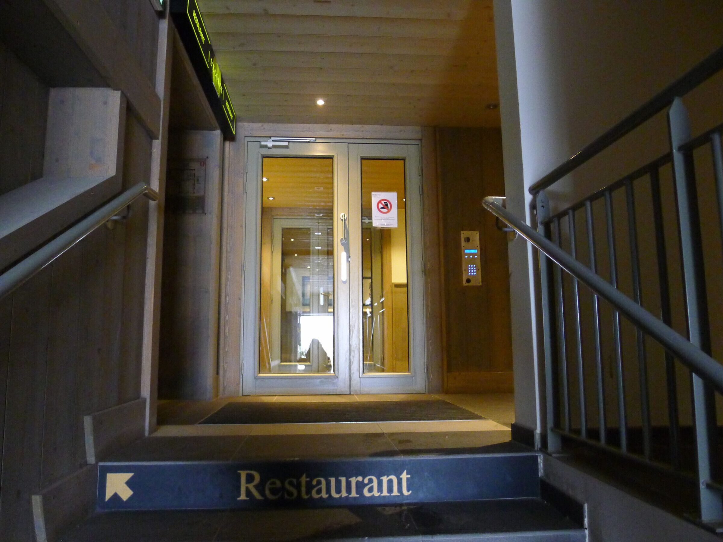 Un escalier menant à l’entrée d’un restaurant, avec une enseigne indiquant la direction.
