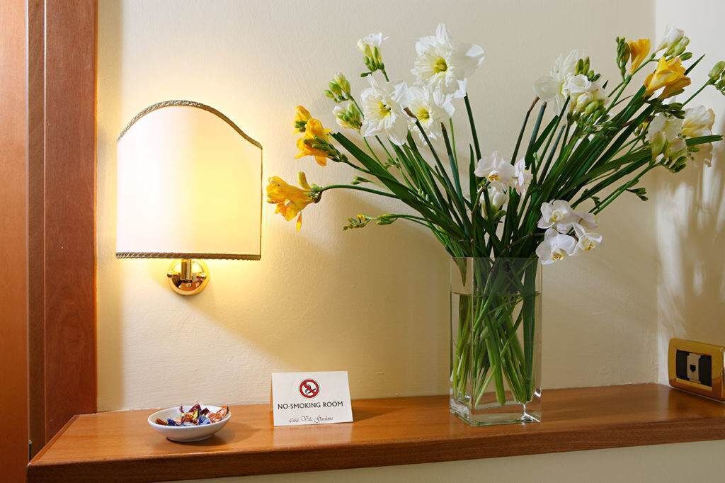 A no-smoking sign, a vase with flowers, and a bowl on a wooden table.