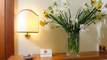 A no-smoking sign, a vase with flowers, and a bowl on a wooden table.