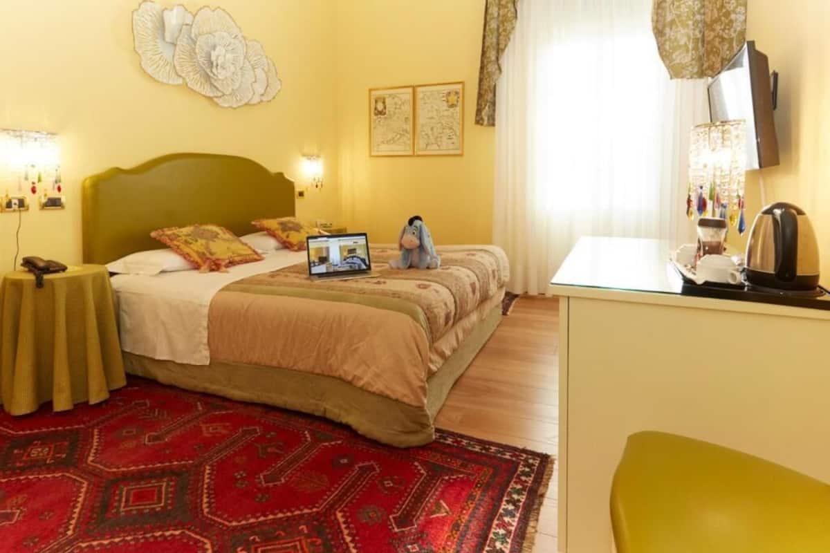 Een hotelkamer met een bed, nachtkastjes, een bureau en een stoel.