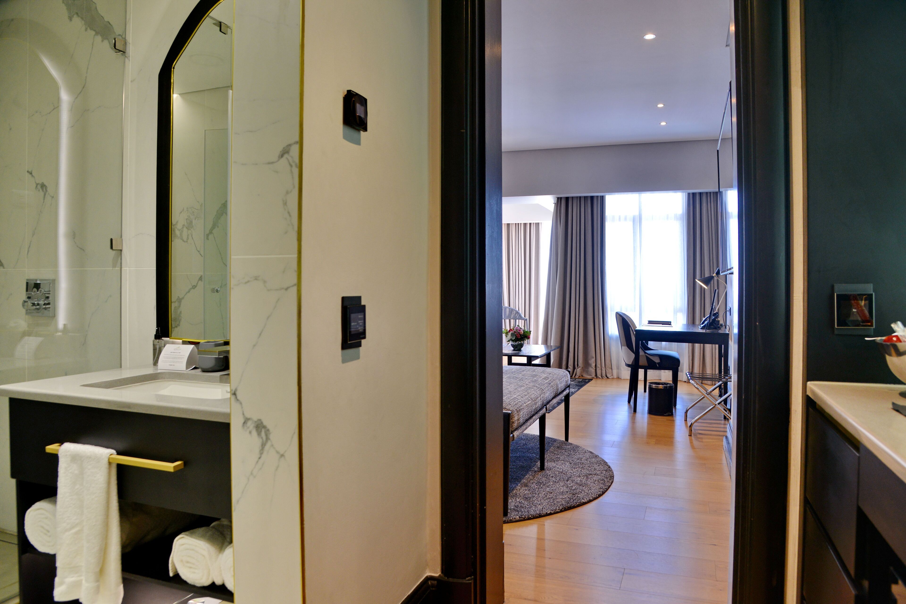 A modern bathroom with a marble sink, a towel rack, and a mirror.