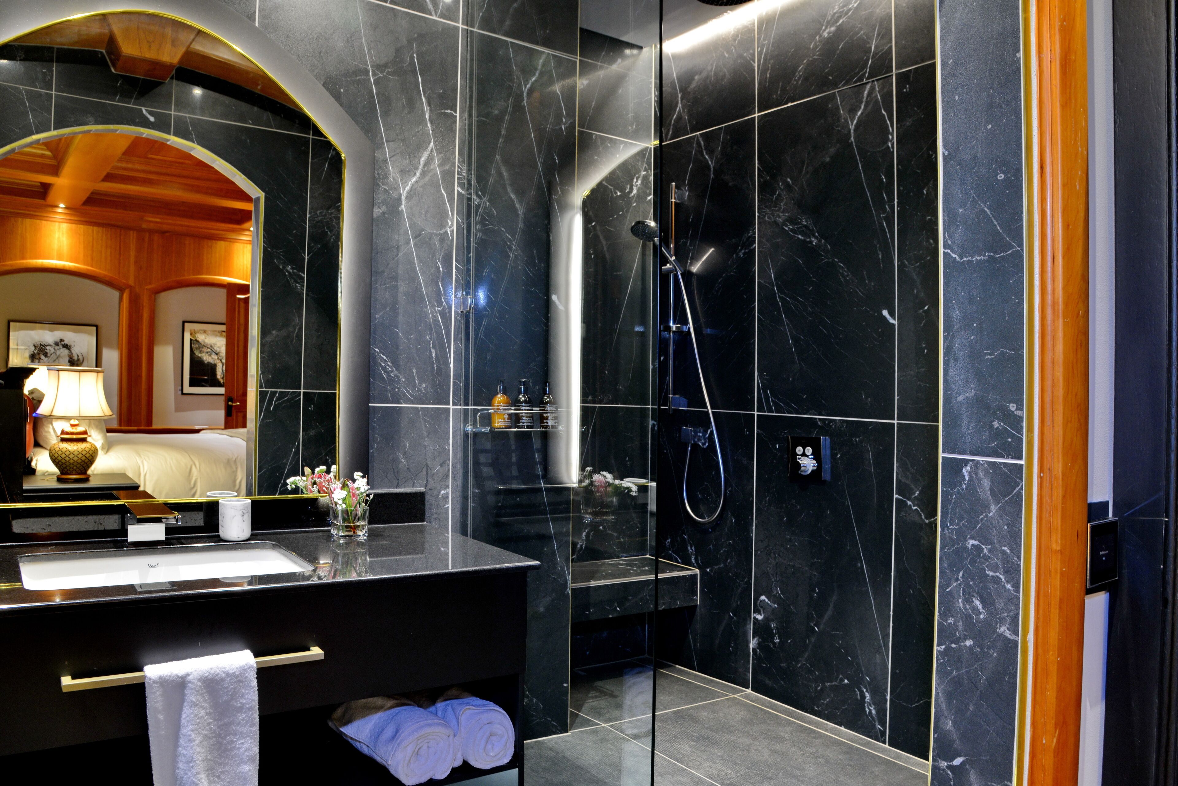A modern bathroom with a large mirror, a sink, and a shower area.