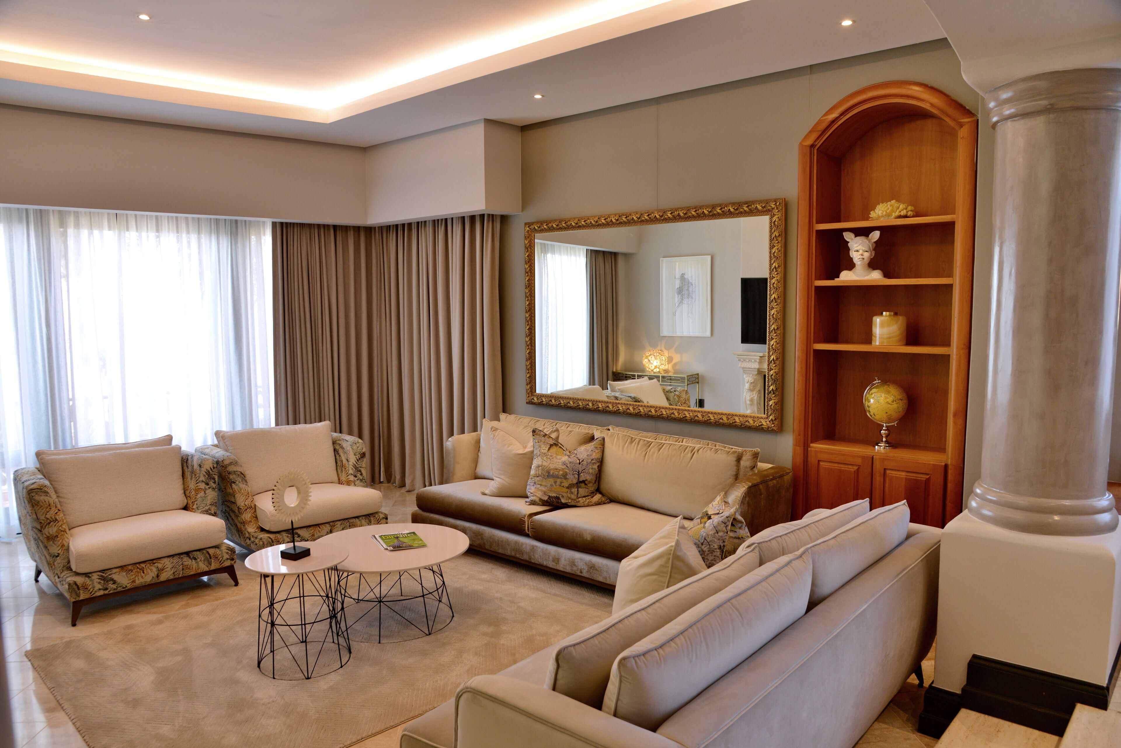 A spacious living room with a large sofa set, a coffee table, and a decorative mirror.