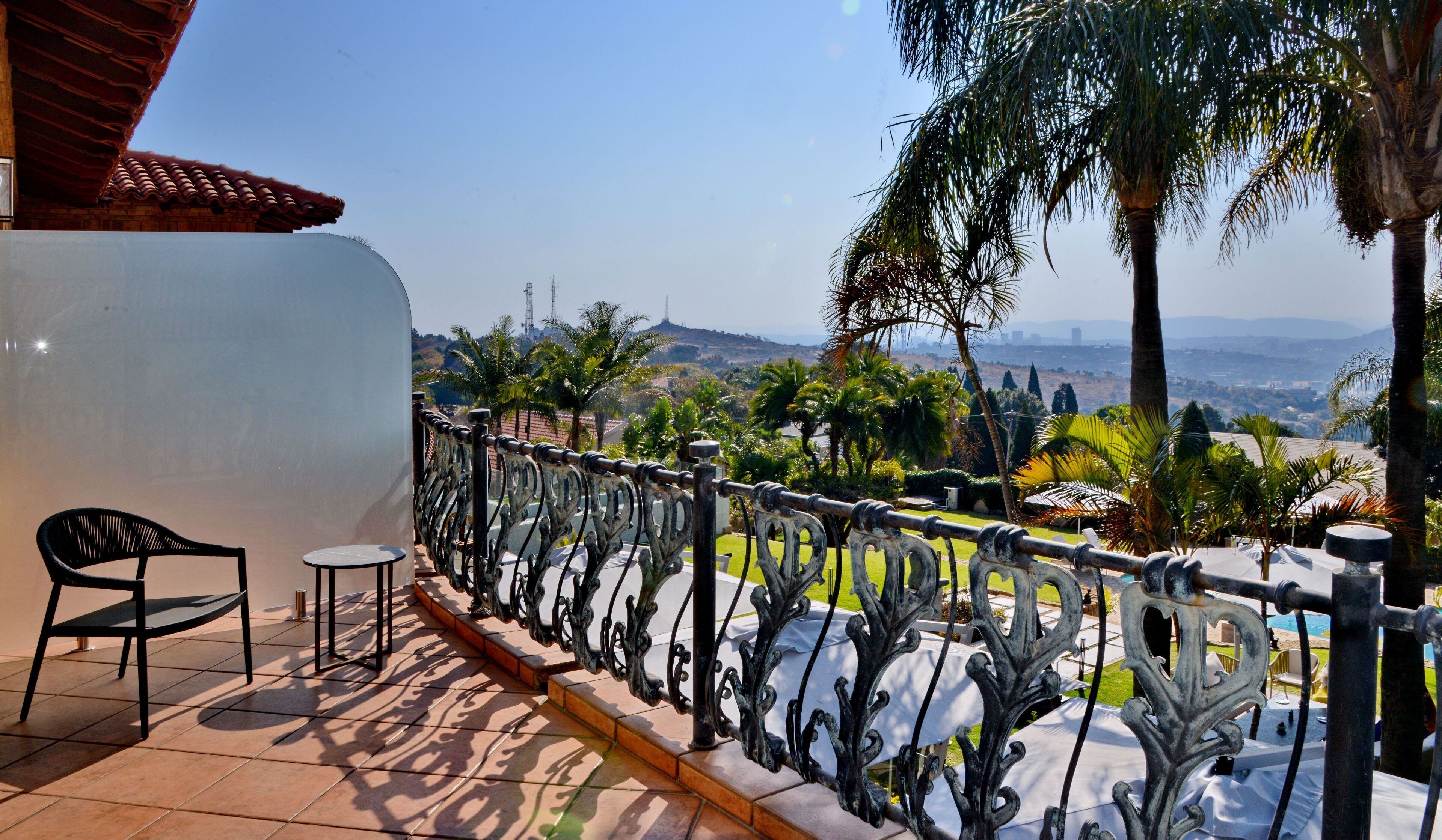 A balcony with a wrought iron railing, a chair, and a small table.