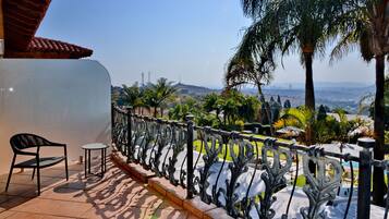 A balcony with a wrought iron railing, a chair, and a small table.