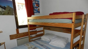 Een stapelbed met een blauw-wit gestreept laken en een rode deken.