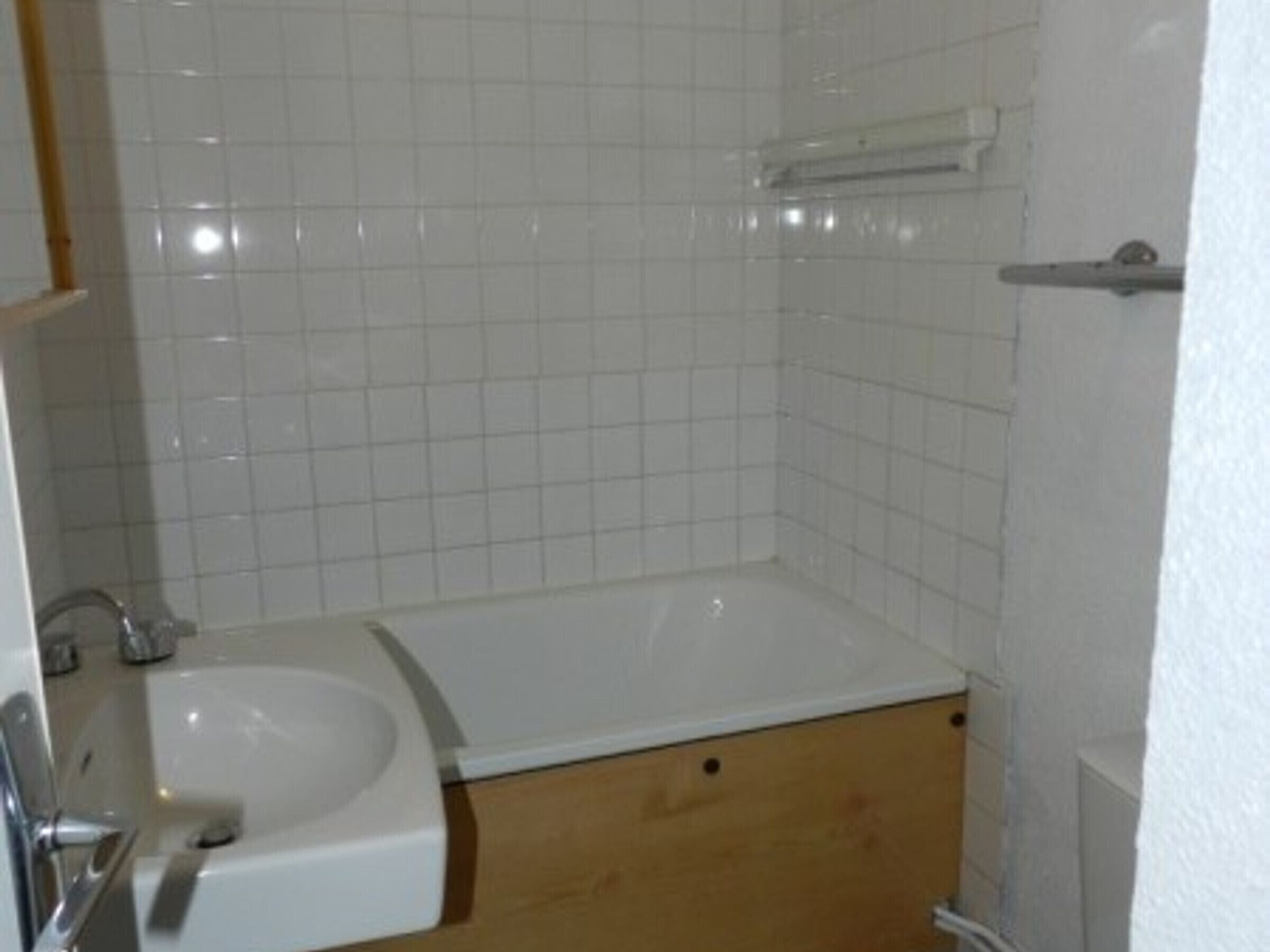 Une salle de bain avec un lavabo blanc, une baignoire et des meubles en bois.