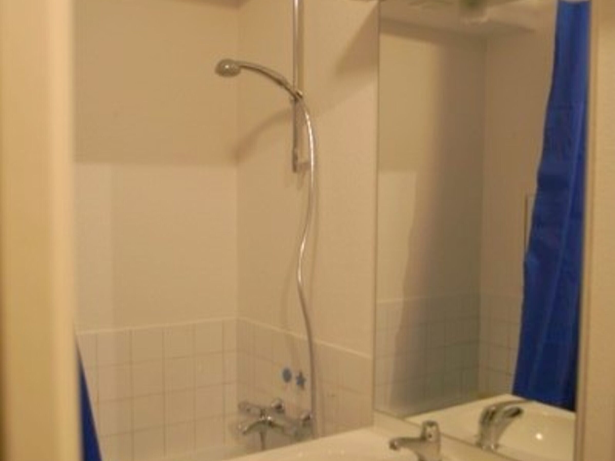 A bathroom with a shower, a sink, and a mirror.
