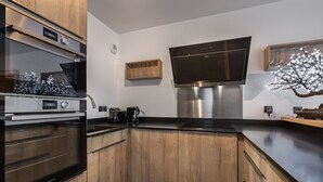 Una cucina moderna con mobili in legno, elettrodomestici in acciaio inossidabile e un piano di lavoro nero.