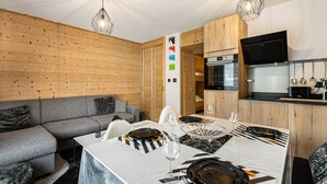 Una cuina moderna amb armaris de fusta, forn integrat i televisió de pantalla plana.