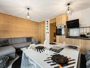 A modern kitchen with wooden cabinetry, a built-in oven, and a flat-screen TV. - Modern apartment Courchevel 4 guests, parking, wifi (Courchevel 1650)