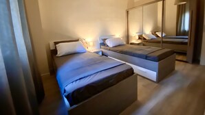 A modern bedroom with two beds, a large mirror, and bedside lamps. - Tranquility and comfort in a modern and original setting! (Mantova)