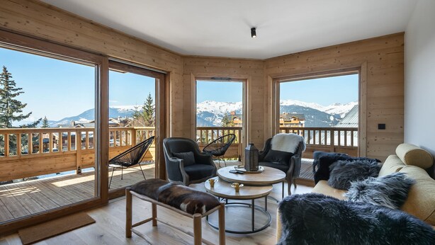 Et trægulv med balkon, sofa, bænk og to stole.