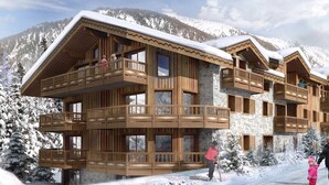En flerplans træchalet med balkoner foran et snøklædt bjerglandskab.