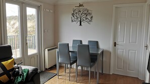Un comedor con una mesa y sillas, un radiador, una puerta y vistas al exterior.