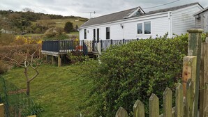 Una casa móvil blanca con terraza cercada y antena parabólica.