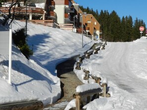 A snow-covered road with a wooden fence and a no-entry sign.