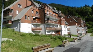 En rad moderna, höga byggnader med balkonger, som kontrasterar mot en bakgrund av grönskande kullar och en klar himmel.