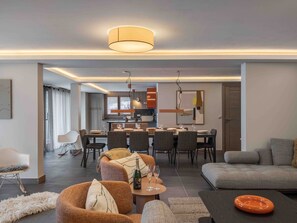 Una sala de estar moderna con un sofá, sillas, una mesa de comedor y una cocina al fondo.