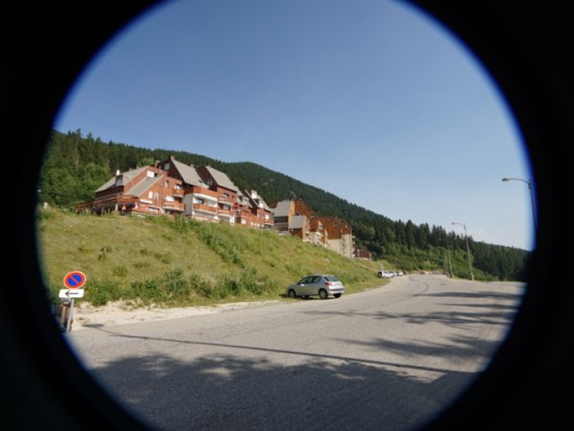 A building with multiple floors, a sloped roof, and a parking area with cars.