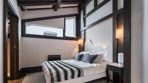 Une chambre moderne comprenant un lit, des tables de chevet, une commode, une fenêtre et une lampe encastrée fixée au mur.