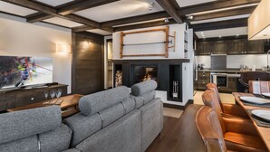 Un salon moderne avec un canapé d’angle gris, un téléviseur à écran plat et une cheminée.