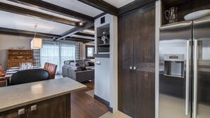 Une cuisine moderne dotée d’un réfrigérateur encastré, de meubles en bois et d’un coin repas avec une table et des chaises.