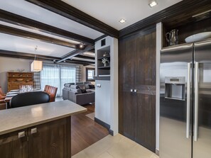 Eine moderne Küche mit integriertem Kühlschrank, Holzschränken und einem Essbereich mit Tisch und Stühlen.