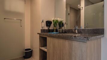 A modern bathroom with a marble countertop, a handheld showerhead, and a large mirror.