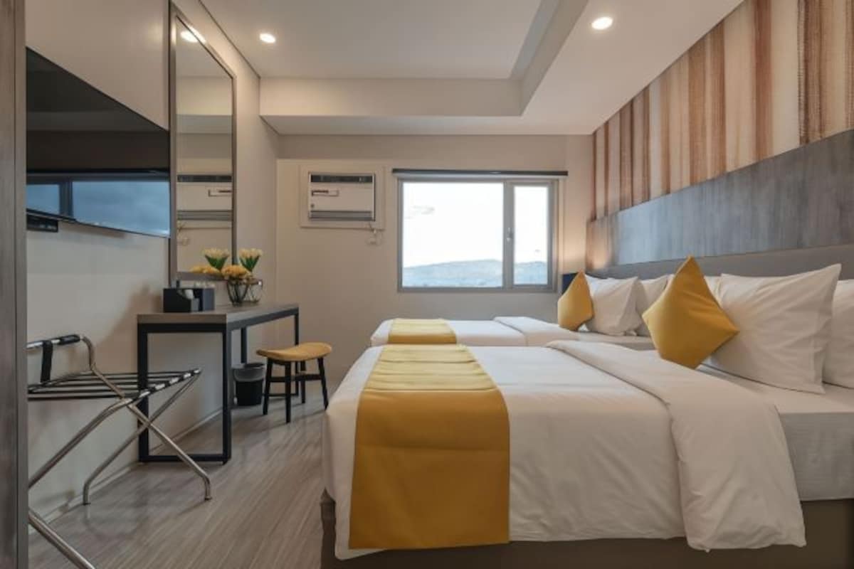 A modern hotel room with a large bed, a desk, and a mirror.