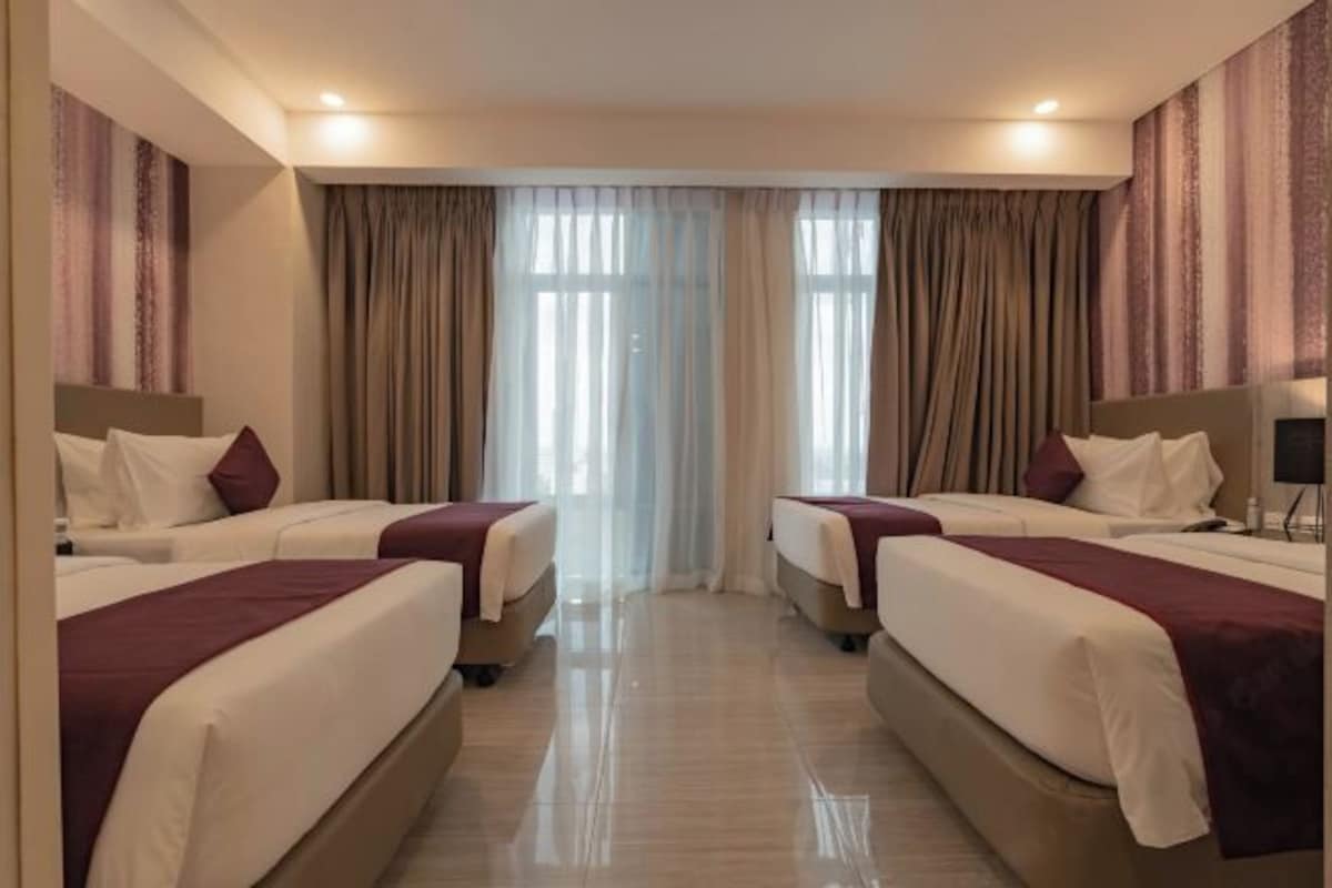 A hotel room with two beds, a large window with curtains, and a modern design.