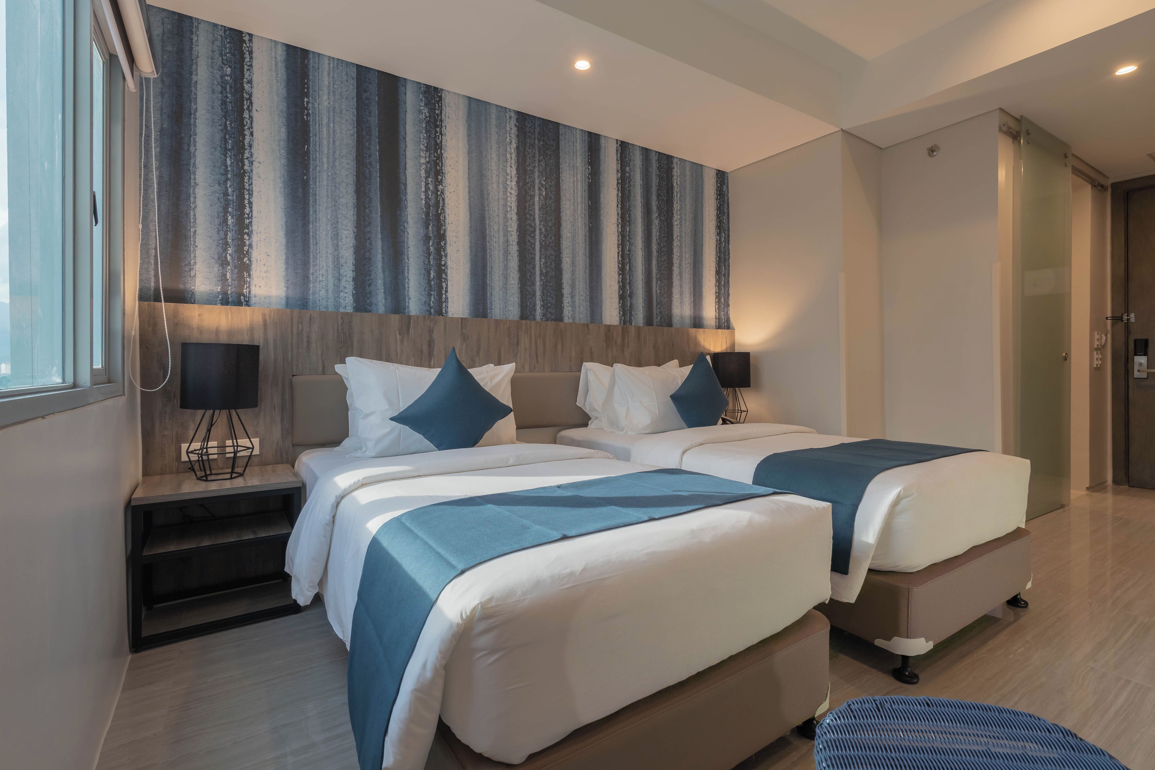 Een moderne hotelkamer met een groot bed, een zithoekje en een groot raam.