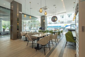 A modern restaurant interior with wicker furniture, pendant lighting, and large windows offering a view of the street. - Bayfront Hotel Cebu - Capitol Site (Cebu City)