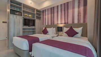 Habitación de hotel con dos camas, un minibar, un televisor y un ventanal grande con cortinas.